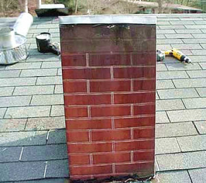 Faux brick metal exterior cover over an oil furnace chimney
