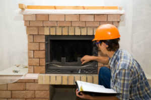 man inspecting fireplace with notebook in hand