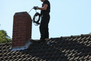 sweep cleaning chimney on roof