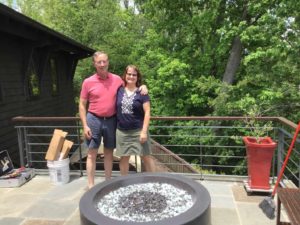 man and woman in t shirt and shorts standing next to fire pit