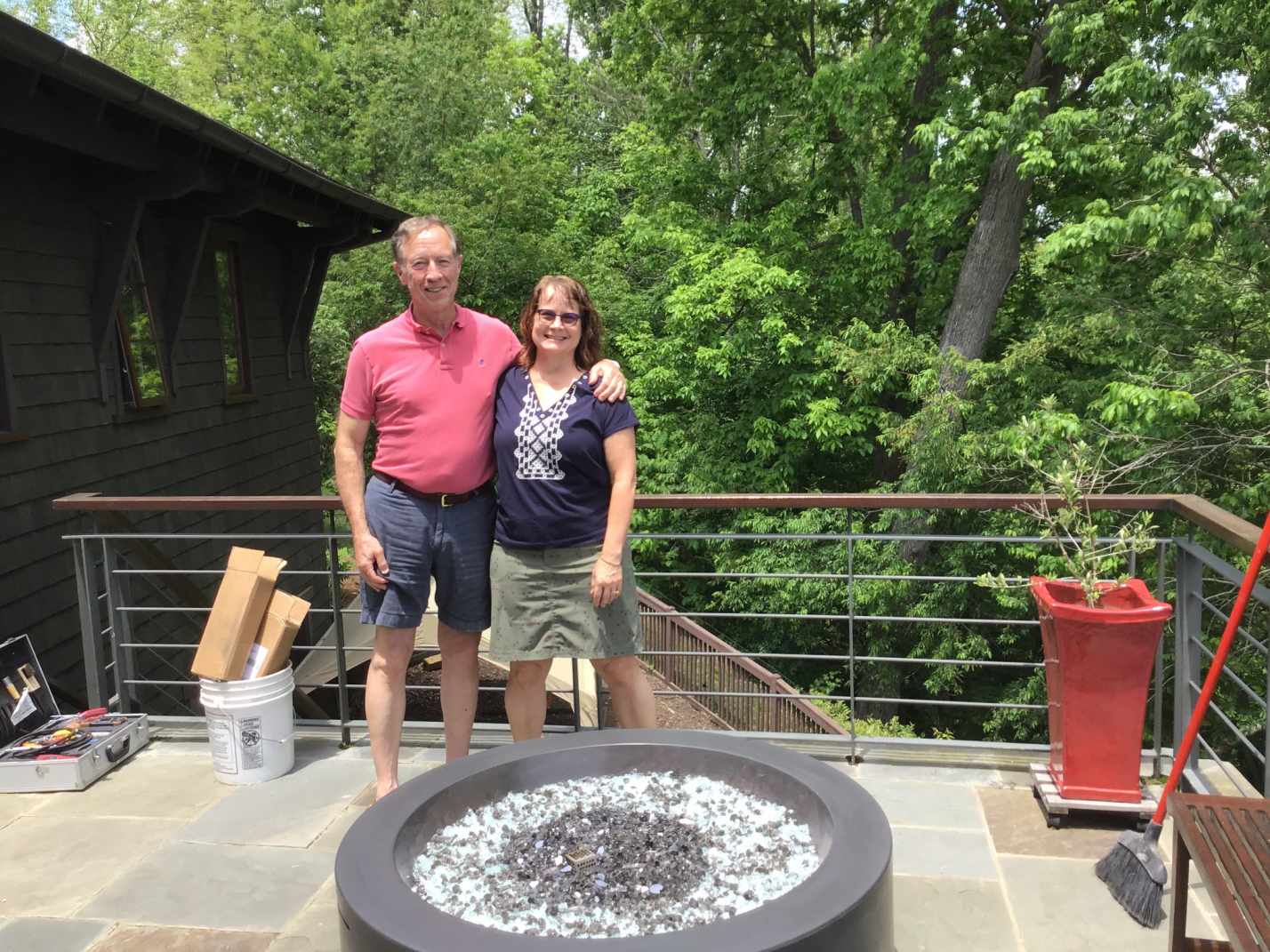 man and woman in t shirt and shorts standing next to fire pit