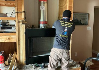 Man installing new fireplace into opening